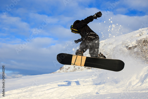 Professional male rider sportsman jumps with snow flakes high acrobatics board trick with grab of snowboard. Recreational activity, extreme active sports, snow kiting ski snowboard