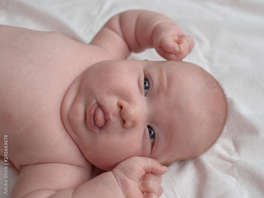 Angry baby with clenched fists. The baby lies on a white linen cloth. Angry baby with clenched fists. The baby lies on a white linen cloth.