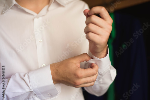Male businessman dresses and adjusts his watch  preparing for a meeting.