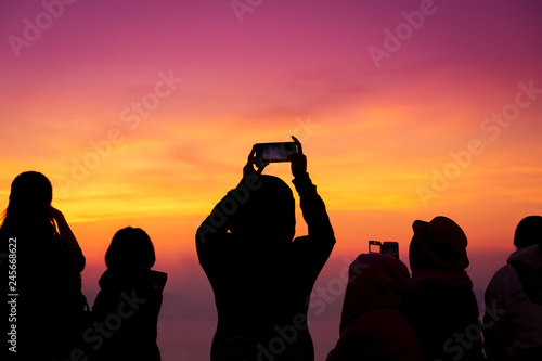 silhouette of people take a photo of gloden and purple sky