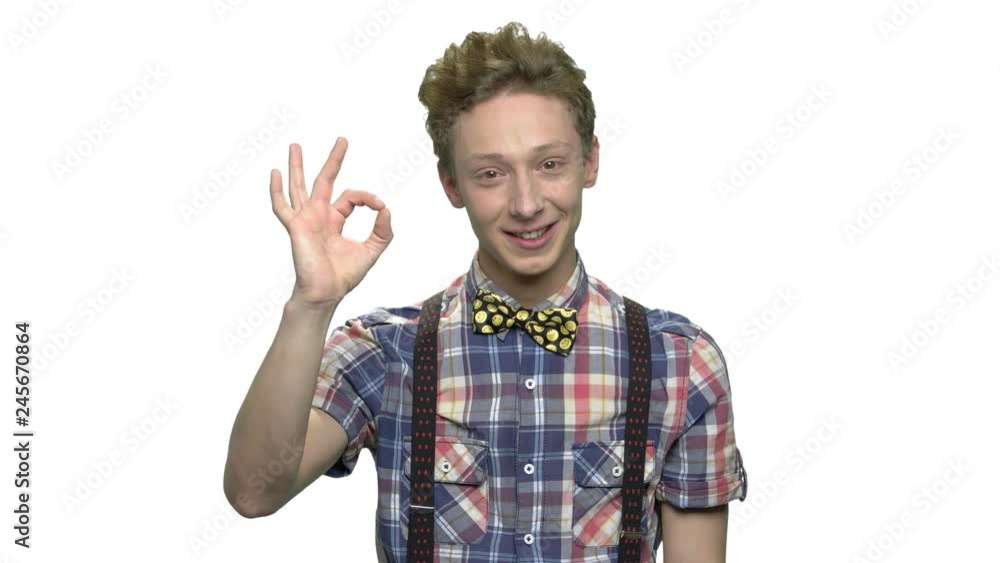 Attractive teenage boy showing OK sign. Cute smiling teen guy giving OKAY symbol over white background. People and gesture concept. Attractive teenage boy showing OK sign. Cute smiling teen guy giving OKAY symbol over white background. People and gesture concept.