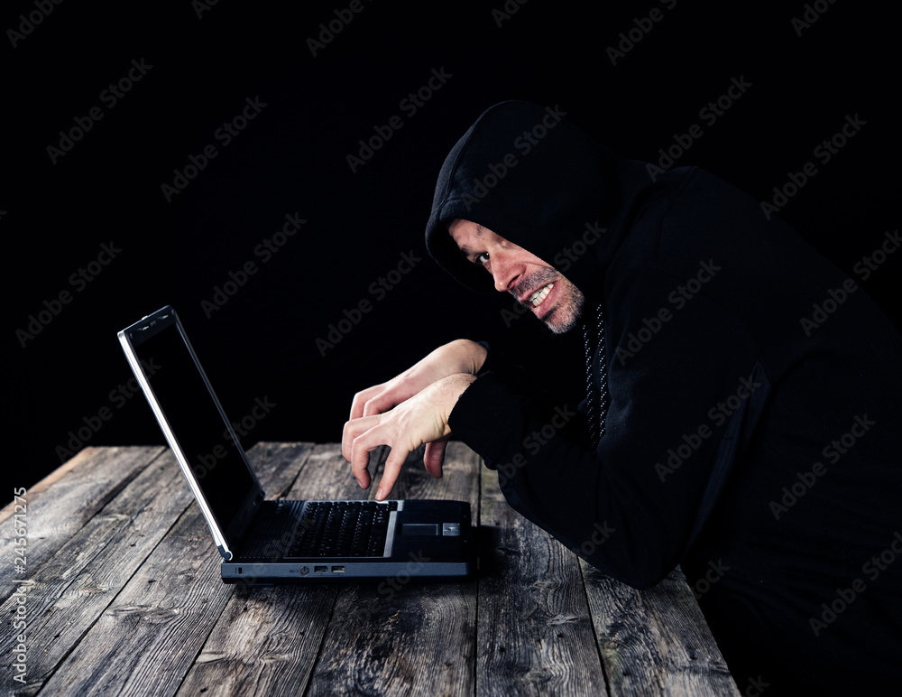 hacker in black hoody with laptop hacker in black hoody with laptop