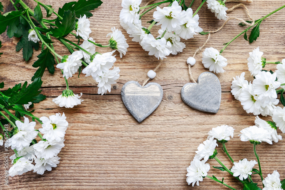 Wooden hearts among white chrysanthemum flowers. Wooden hearts among white chrysanthemum flowers.