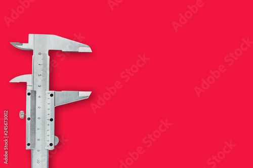 One metal vernier caliper on red table with copy space for your text. Top view. Industrial concept photo