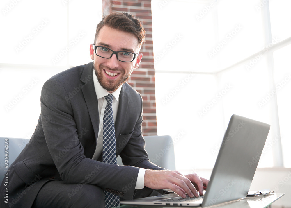 Young businessman using laptop and smiling Young businessman using laptop and smiling