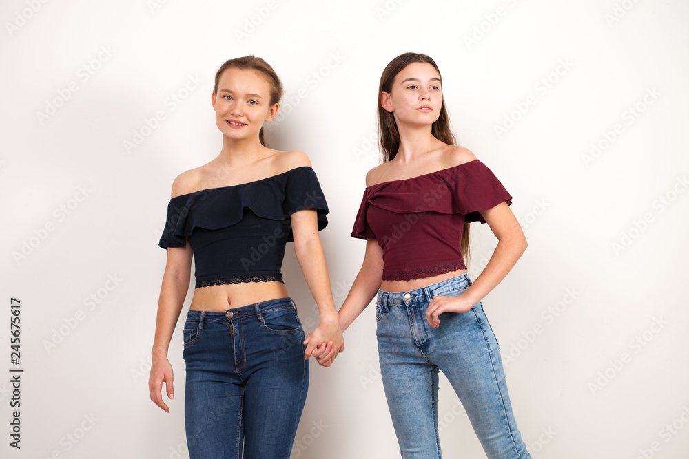 Two young girlfriends posing against wall Two young girlfriends posing against wall