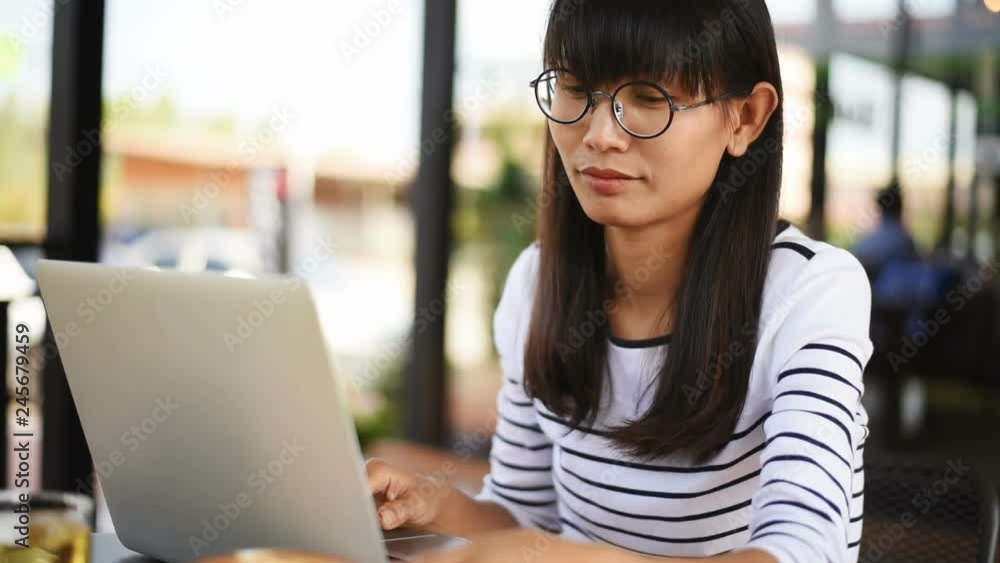 Beautiful young Asian girl with tablet in cafe drinking coffee and working on tablet. Beautiful young Asian girl with tablet in cafe drinking coffee and working on tablet.