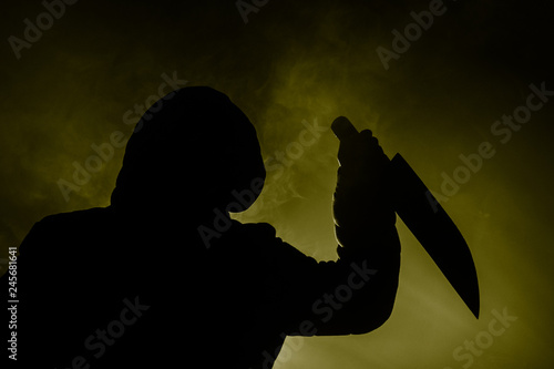 Tapet A dangerous hooded man standing in the dark and holding a knife