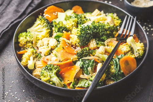 Vegan wok stir fry with broccoli and carrot in black dish. photo