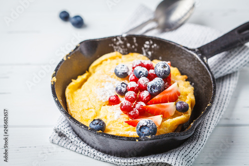Dutch baby pancake with berries in a cast-iron pan.