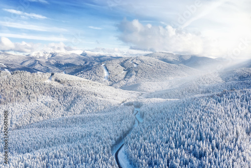Aerial view on the road and forest at the winter time. Natural winter landscape from air. Forest under snow a the winter time. Landscape from drone