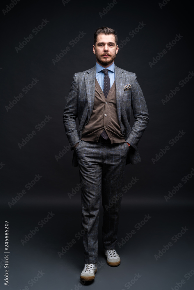Fototapeta premium Full length portrait of a fashion male model over black background. Looking at camera.