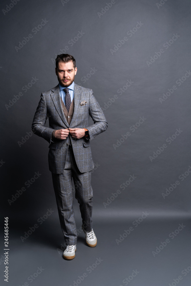 Full length portrait of a fashion male model over grey background. Looking at camera. Full length portrait of a fashion male model over grey background. Looking at camera.