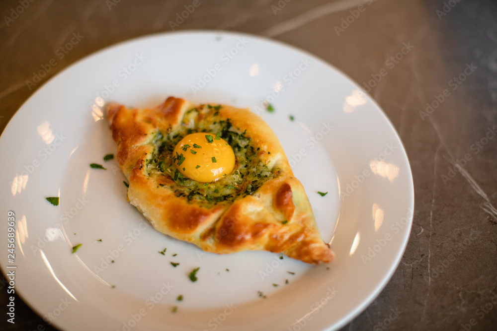 Georgia adjarian Khachapuri with spinach, cheese and yolk filling on plate