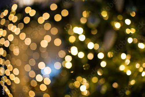 Out of focus texture background of Christmas tree with ornaments and Christmas lights.