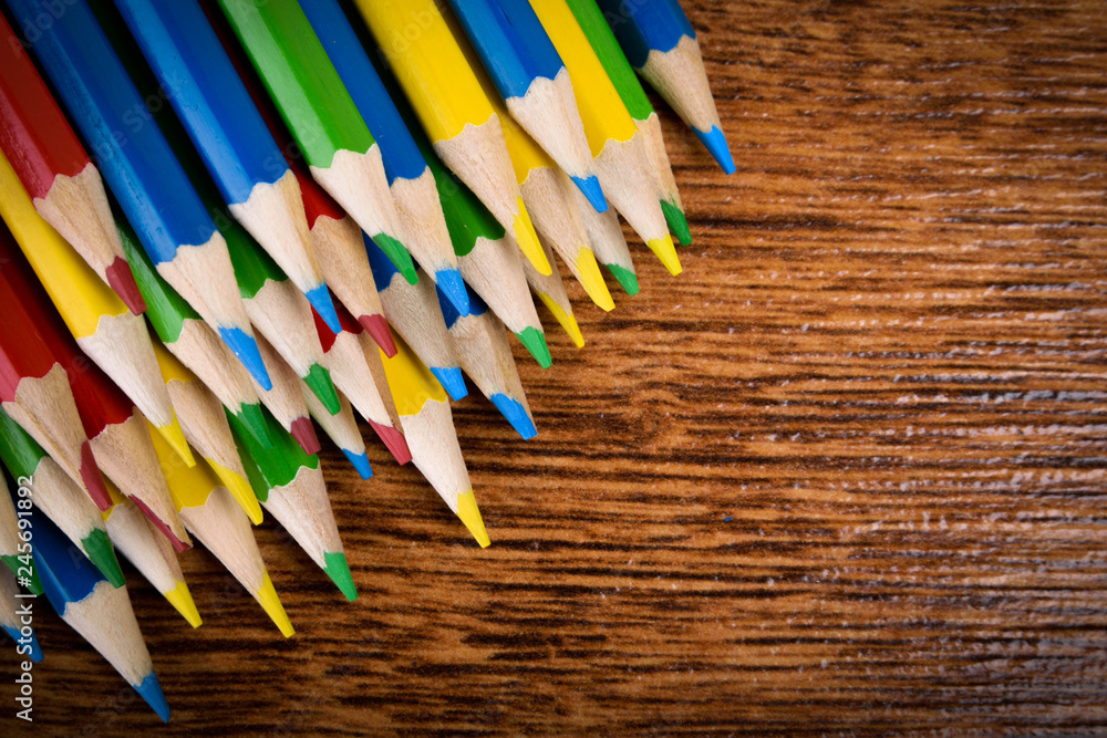 Different colored pencils on the brown wooden table background .Top view .Close up .Color .Pencil.Set Different colored pencils on the brown wooden table background .Top view .Close up .Color .Pencil.Set