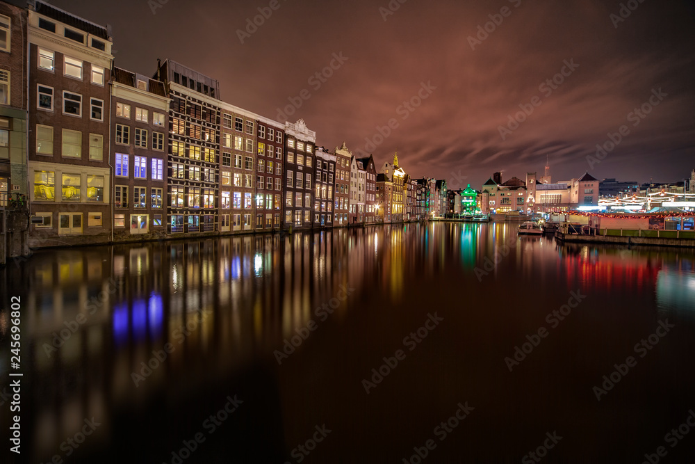 Iconic Amsterdam view with its canals and illuminated houses in front the train station, Netherlands