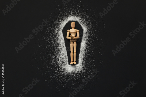 Wooden mannequin in coffin made of sugar on black photo