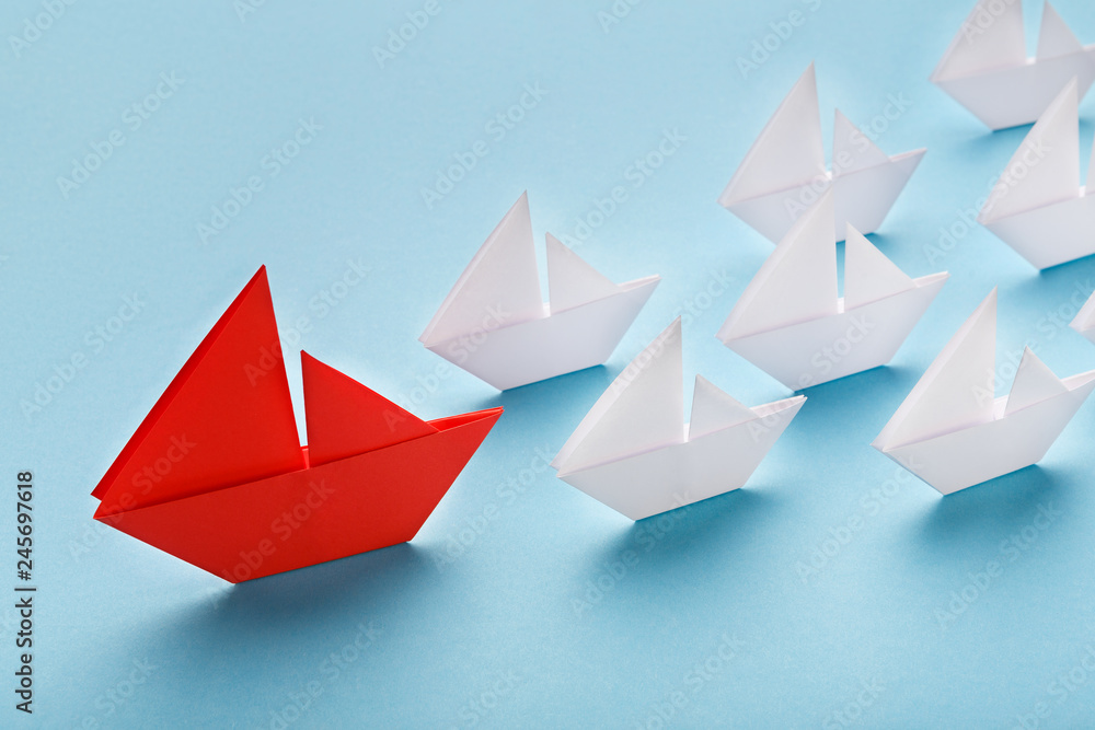 Red paper boat leading white ships, panorama Red paper boat leading white ships, panorama