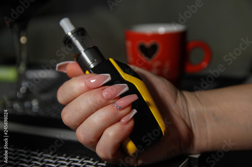 Woman s hands holding electronic cigarette. Nail art on hers nails.