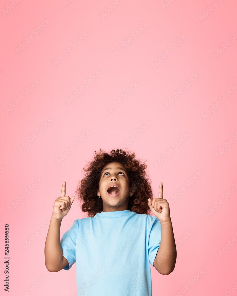 African-american girl pointing fingers up on copy space African-american girl pointing fingers up on copy space