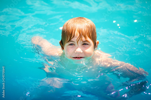Little blonde child with strabismus in the blue swimming pool
