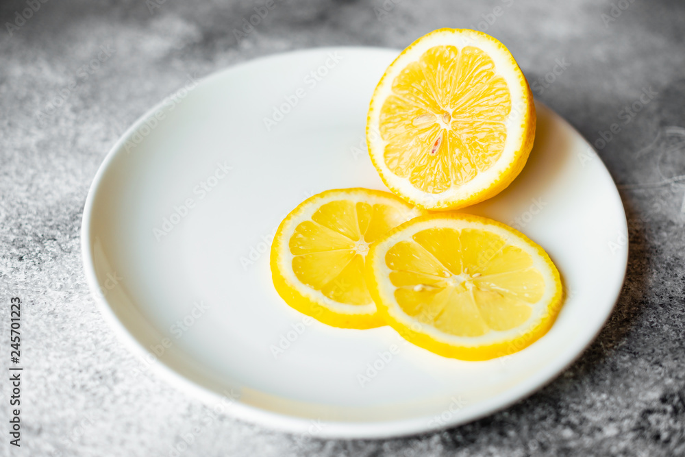 Lemon, fruit, citrus. A fresh juicy lemon on a white plate on a concrete background Lemon, fruit, citrus. A fresh juicy lemon on a white plate on a concrete background