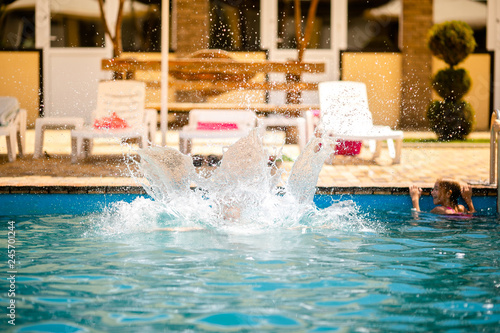 Little blonde girl in bright pink swimsuit having fun in the summer blue swimming pool photo