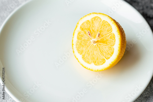 Lemon, fruit, citrus. A fresh juicy lemon on a white plate on a concrete background