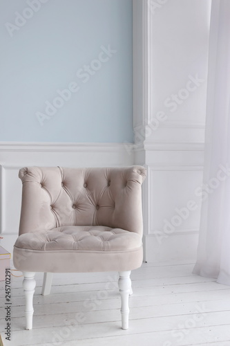 gray sofa chair in luxury apartments with blue walls and white wooden floor © Tetiana