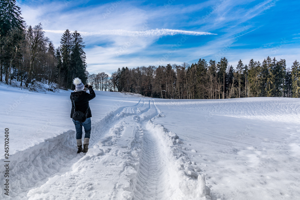 Junge Frau fotografiert Landschaft beim Winterspaziergang