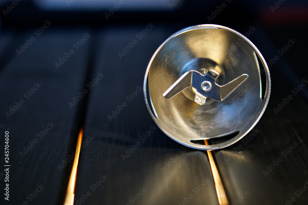 A sharp knife nozzle for a blender lies on a black wooden surface. Device for cooking A sharp knife nozzle for a blender lies on a black wooden surface. Device for cooking