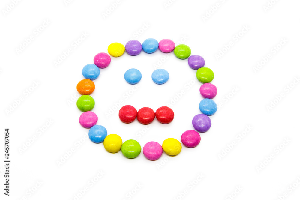 Smiley from multicolored chocolate glazed candies on white Smiley from multicolored chocolate glazed candies on white