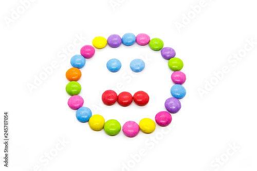 Smiley from multicolored chocolate glazed candies on white