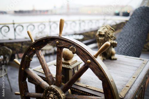 Obraz na plátně Wooden helm or sailing wheel with decorative ornaments on large ship floating up