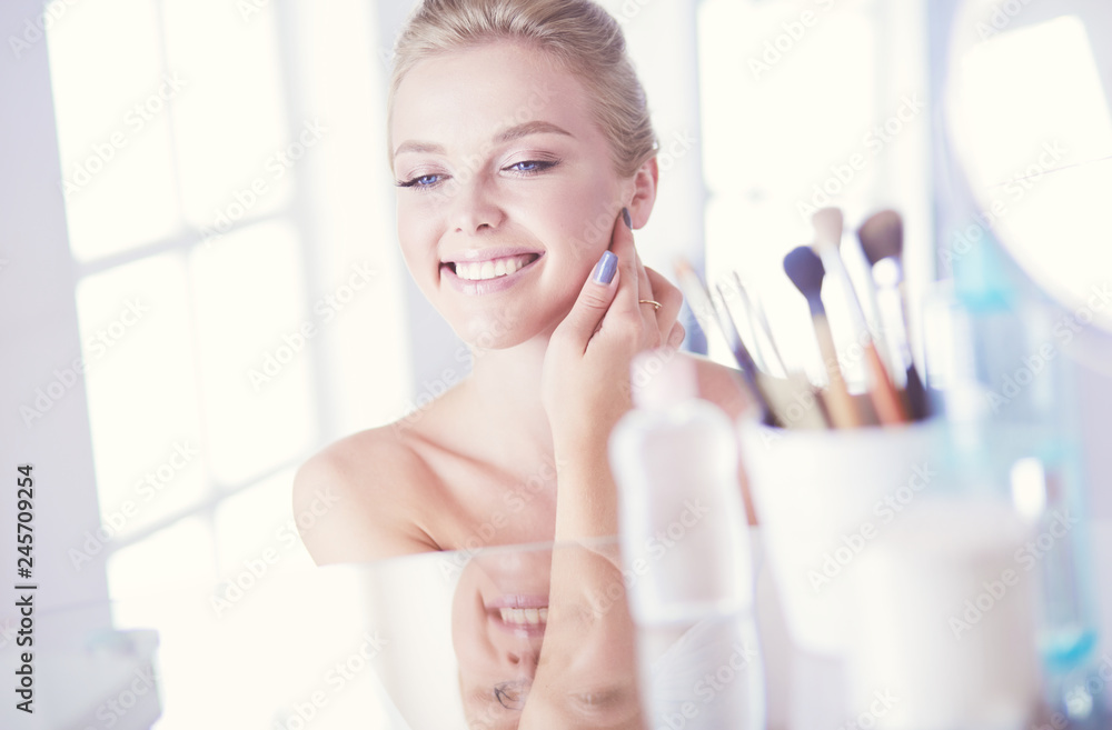 Young woman in bathrobe looking in bathroom mirror Young woman in bathrobe looking in bathroom mirror
