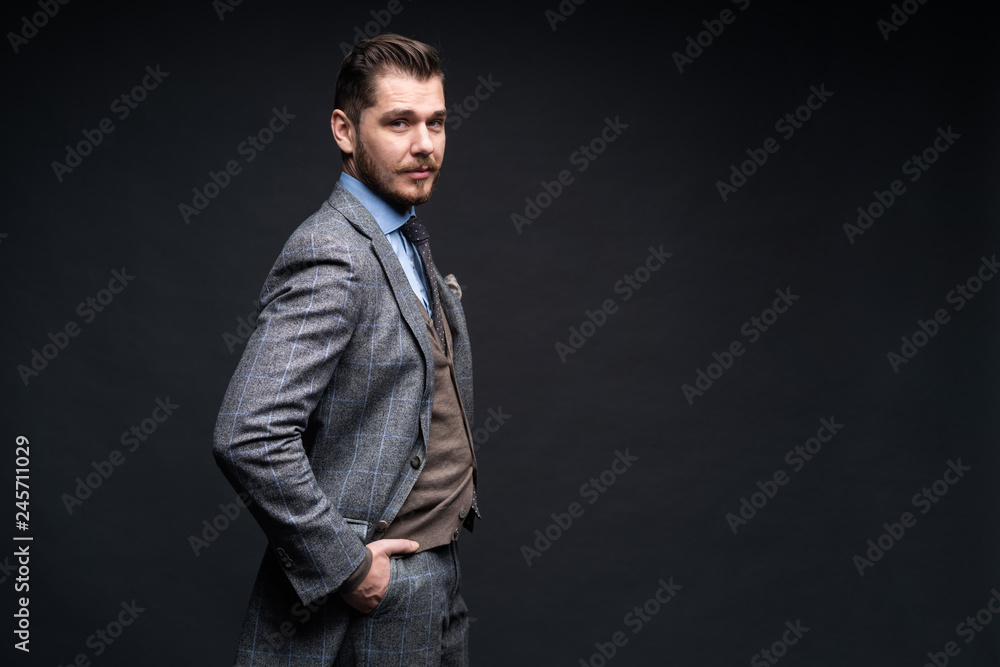 A confident elegant handsome young man standing in front of a black background in a studio wearing a nice suit. A confident elegant handsome young man standing in front of a black background in a studio wearing a nice suit.