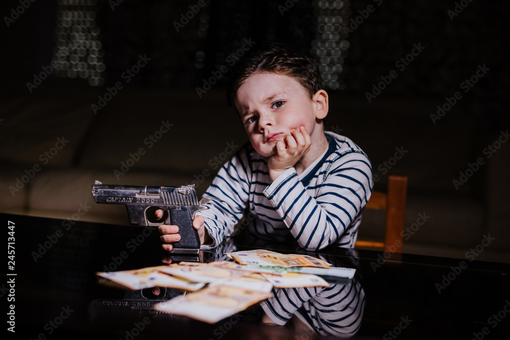 Little mobster with gun and money on the table 