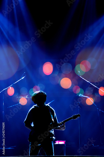 Asian Musician playing the guitar on black background with spot light, bokeh and lens flare, musical concept