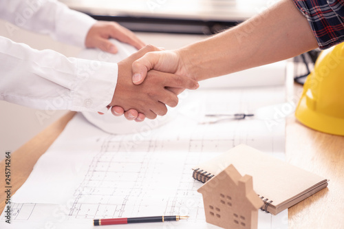 architect or civil engineer and client or customer shaking hands for agreement of home or building plan,plan is fake only for stock photo.