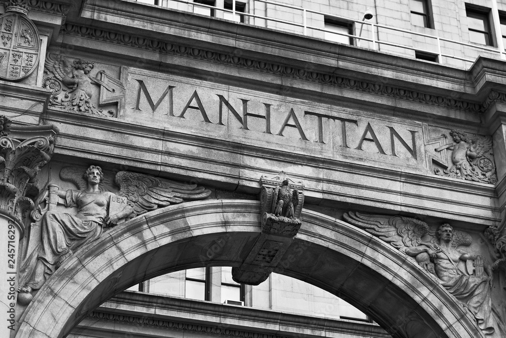 Word Manhattan engraved on the old building facade in NYC, USA