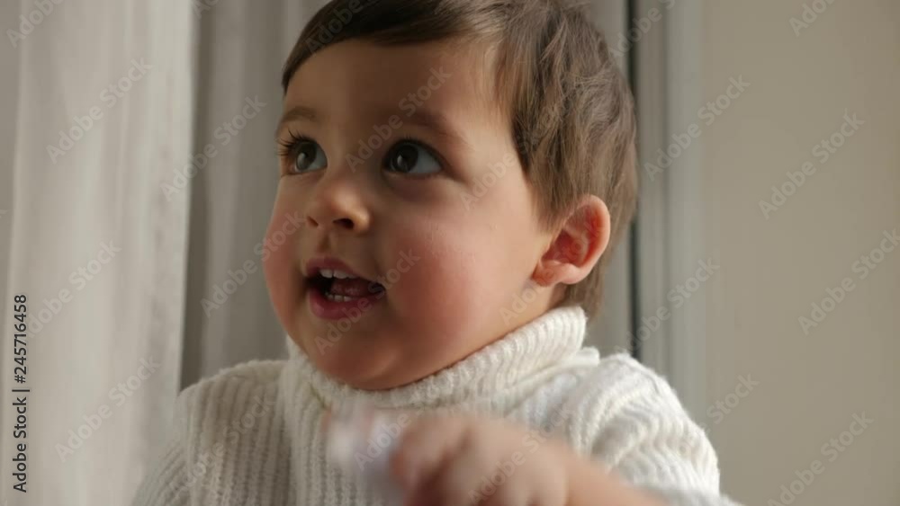 baby boy in white knitted sweater sitting by the window in winter baby boy in white knitted sweater sitting by the window in winter