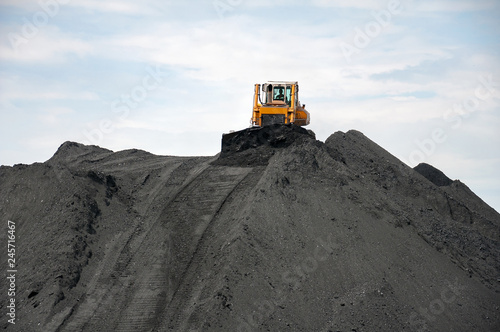 caterpillar tractor and travelling crane load black coal on supply field of thermoelectric power station