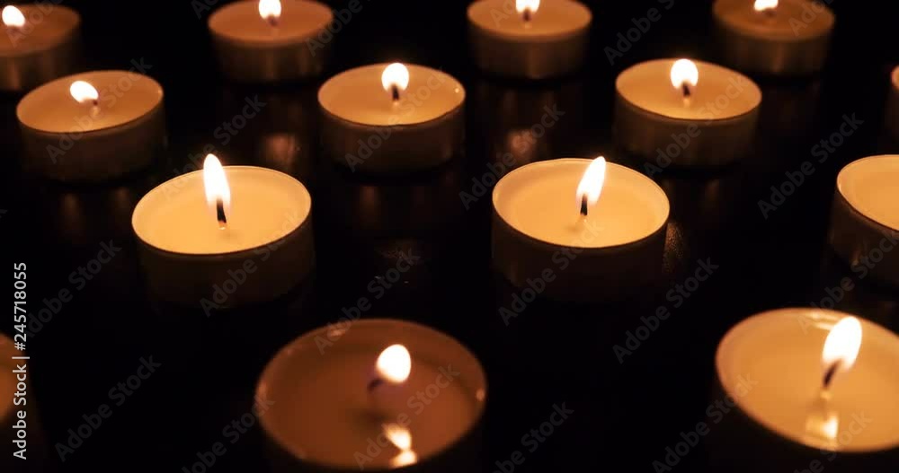 Camera Movement Past Burning Candles. The camera moves slowly along the field with burning small candles in total darkness. Flames moving by the movement of air. Filmed at a speed of 120fps