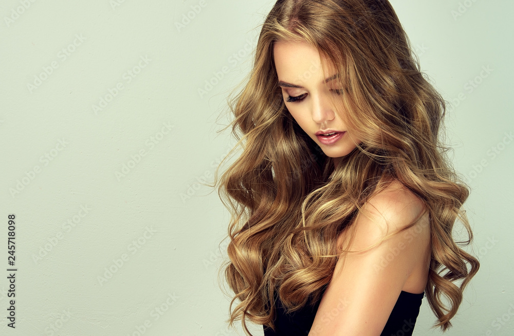 blonde girl with long and shiny wavy hair . Beautiful smiling woman model  with curly hairstyle . Stock Photo | Adobe Stock