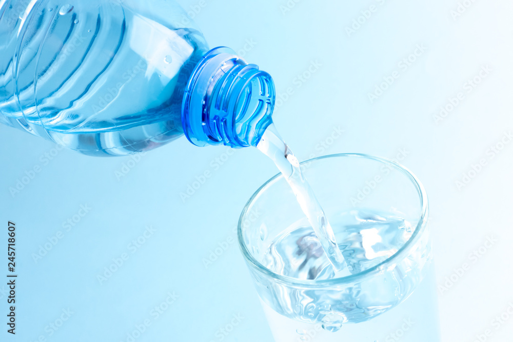 Pouring clean water from a plastic bottle. Glass of water in blue. Pouring clean water from a plastic bottle. Glass of water in blue.