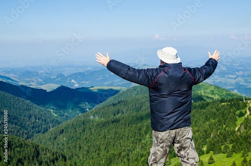 Man with spread arms in a joyful pose, in a mountain landscape