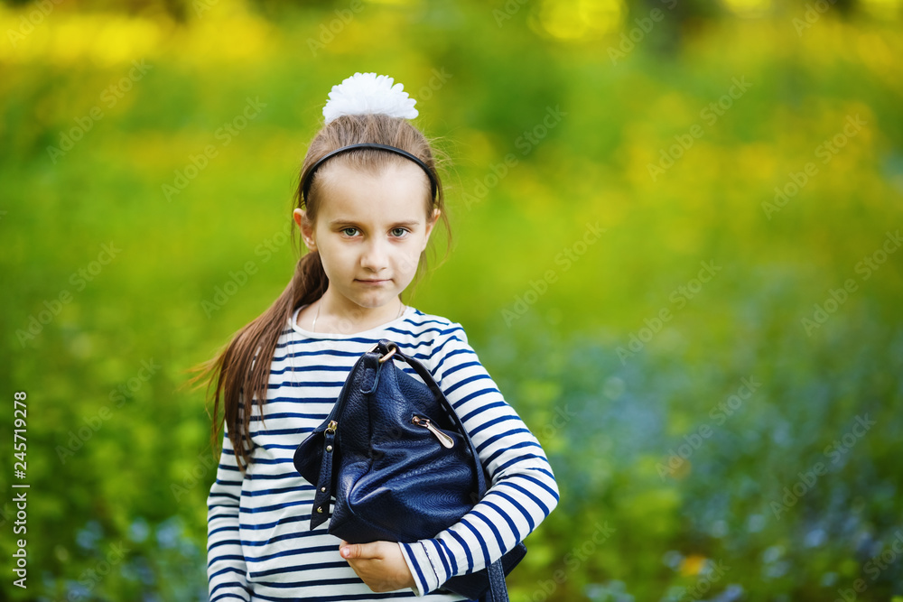 Girl with handbag posing outdoors. Child in the park. Selective focus. Girl with handbag posing outdoors. Child in the park. Selective focus.