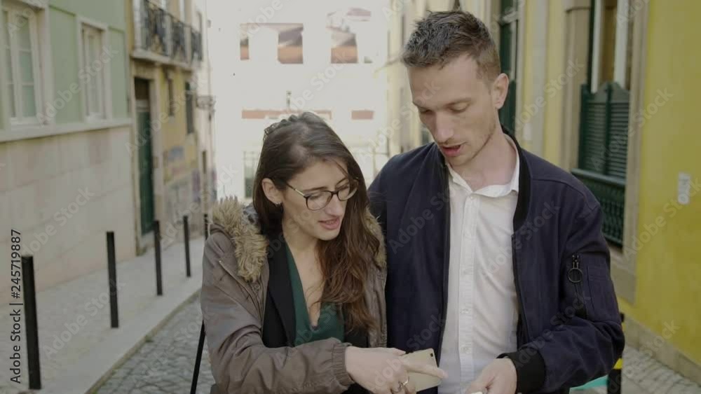 Smiling young couple using smartphones outdoor. Happy young people strolling on street with digital devices. Technology concept Smiling young couple using smartphones outdoor. Happy young people strolling on street with digital devices. Technology concept