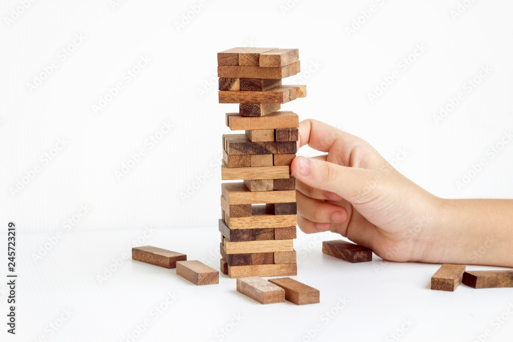 hand pulling out or placing wood block on the tower in modern office, plan and strategy in business with white background. hand pulling out or placing wood block on the tower in modern office, plan and strategy in business with white background.